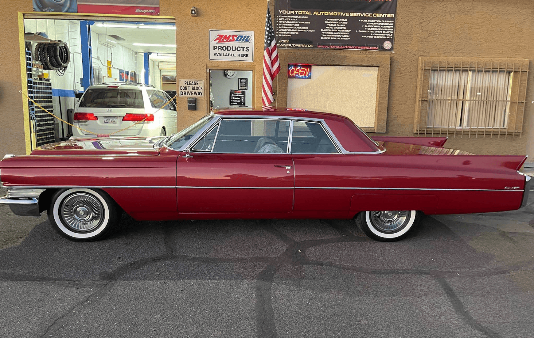 Restored classic red Cadillac outside Total Automotive and Performance